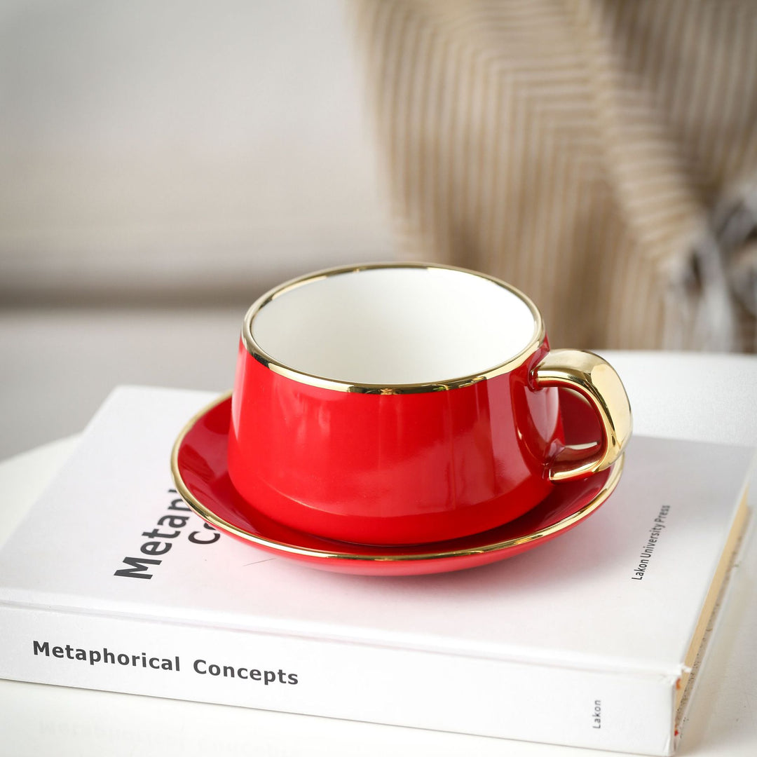 Elegante Porzellan-Tasse mit Untertasse und skulpturellem Goldhenkel
