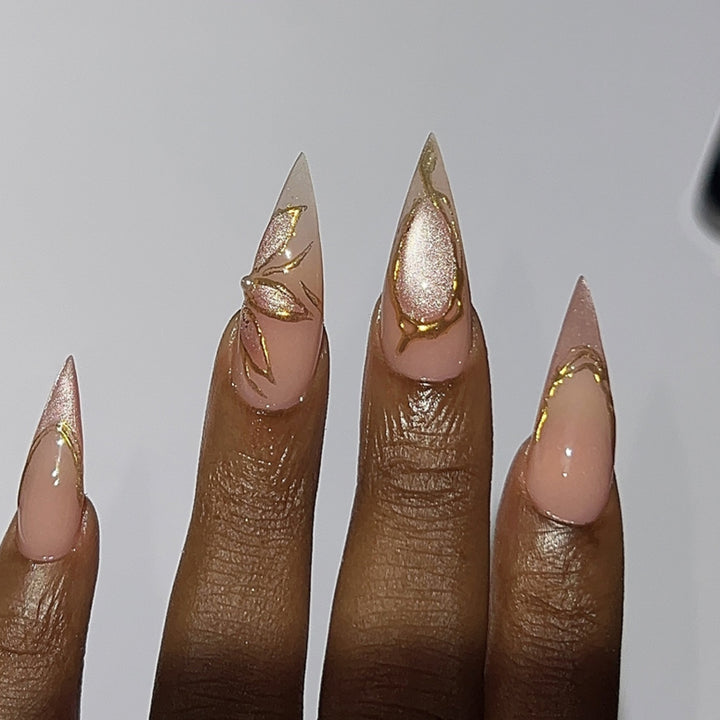 Kunstvolle Stiletto-Nägel mit Goldakzenten Karnz