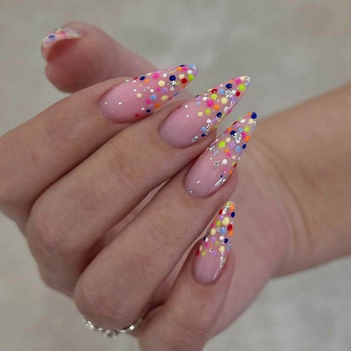 Kunstnagelset mit bunten Glitzerpunkten und eleganten Spitzen Karnz