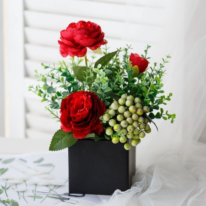 Lebensechte Blumenarrangement in dekorativem quadratischen Pflanzgefäß