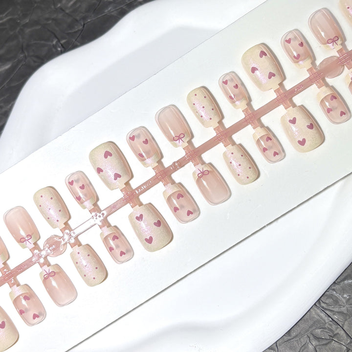 Dekorativer Press-On-Nagelset mit Herz- und Bogenmotiven