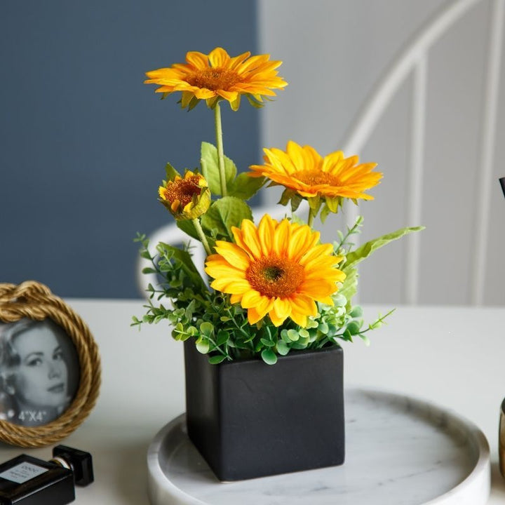 Lebensechte Blumenarrangement in dekorativem quadratischen Pflanzgefäß