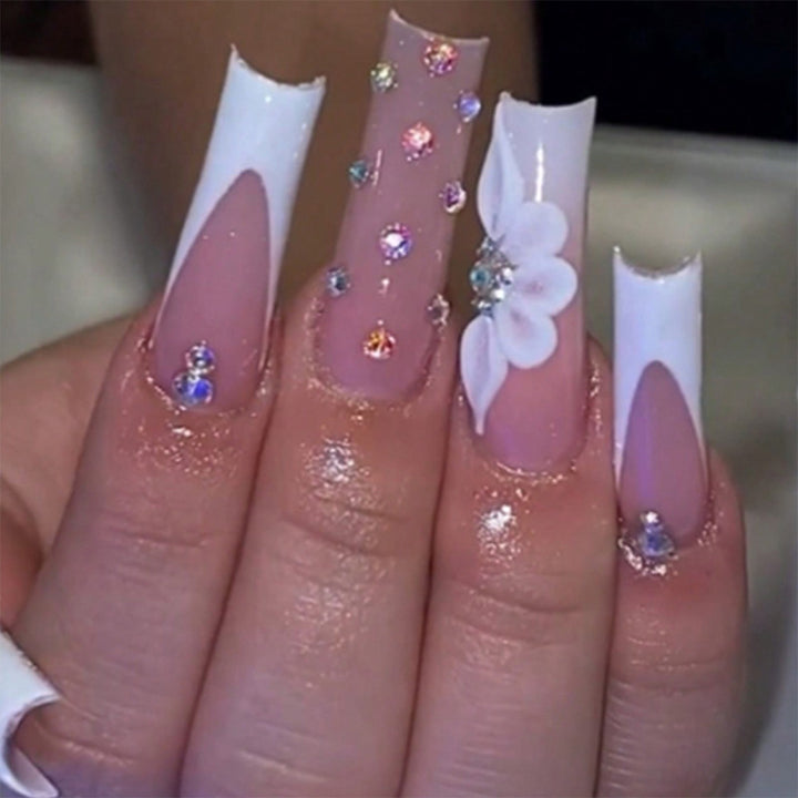 Kunstvolle Stiletto-Nägel mit floralen Akzenten und Strass-Details Karnz