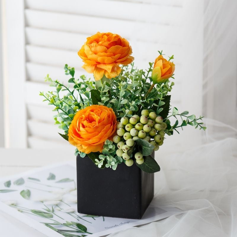 Lebensechte Blumenarrangement in dekorativem quadratischen Pflanzgefäß