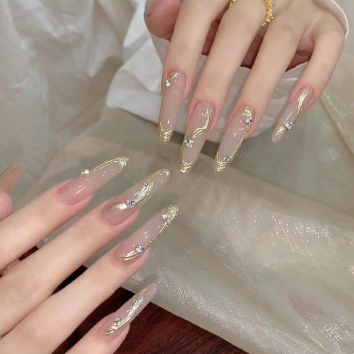 Kunstnagelset mit elegantem Gold-Design und funkelnden Applikationen Karnz