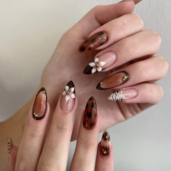 Kunstvolle Stiletto-Nägel mit eleganten Blumenmotiven und Glitzerakzenten Karnz