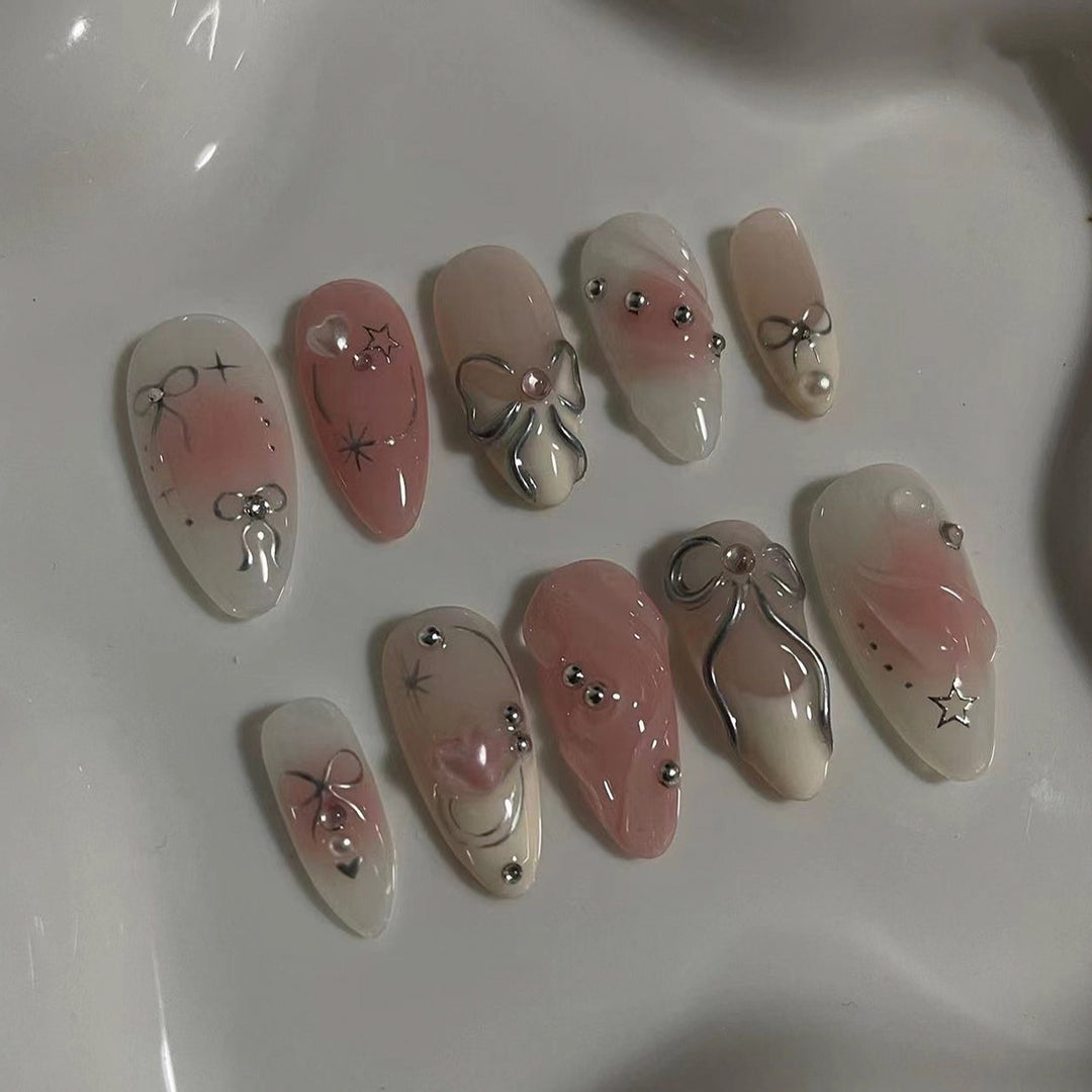 Kunstvolle Nagelspitzen mit Glitzer- und Schleifenmotiven Karnz