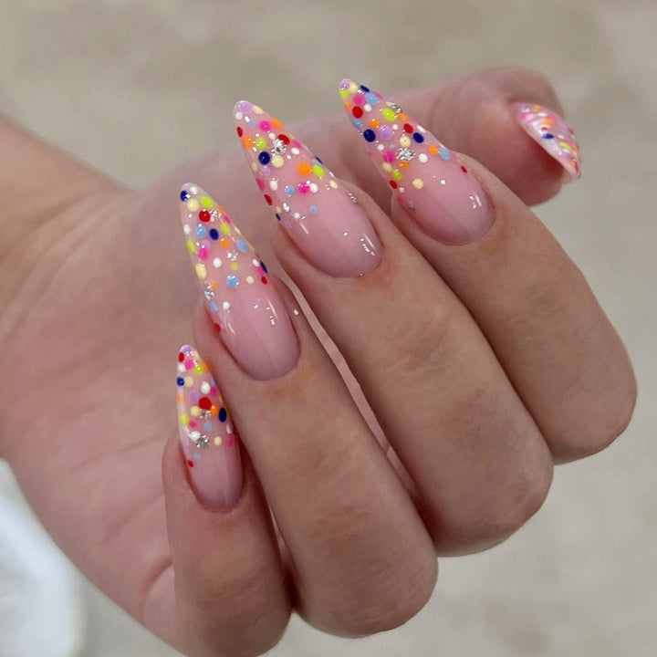 Kunstnagelset mit bunten Glitzerpunkten und eleganten Spitzen Karnz