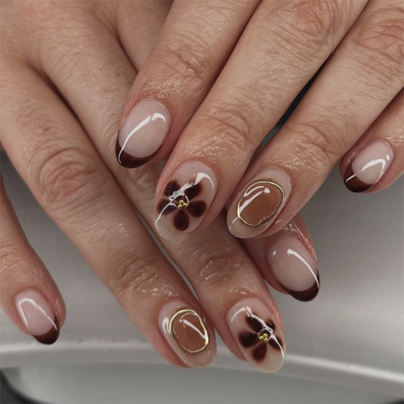 Elegante Nagelkunst mit floralen Akzenten und goldenen Details Karnz