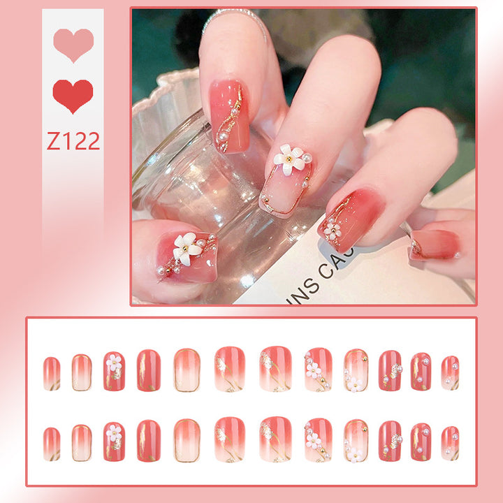Kunstnagelset mit eleganten Blumendekoren und glamourösen Perlenakzenten Karnz