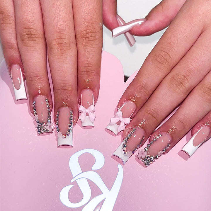 Kunstnagelset mit sorgfältigen Schleifen- und Glitzerverzierungen Karnz