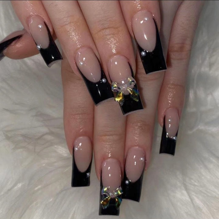 Kunstnagelverzierung mit eleganten Schleifen und Strass Karnz