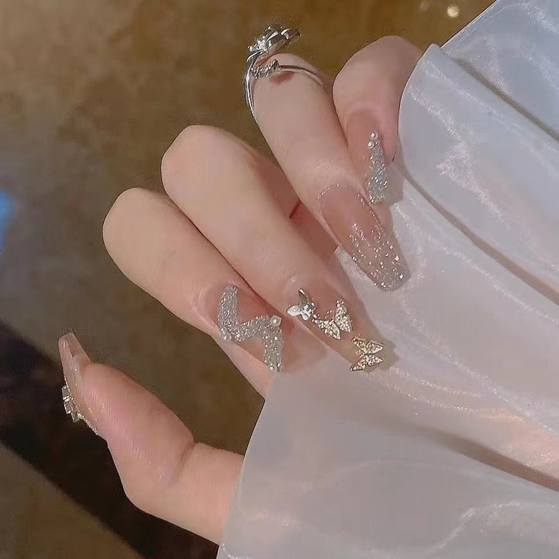 Glamouröse Nagelkunst mit Strass- und Schmetterlingselementen Karnz