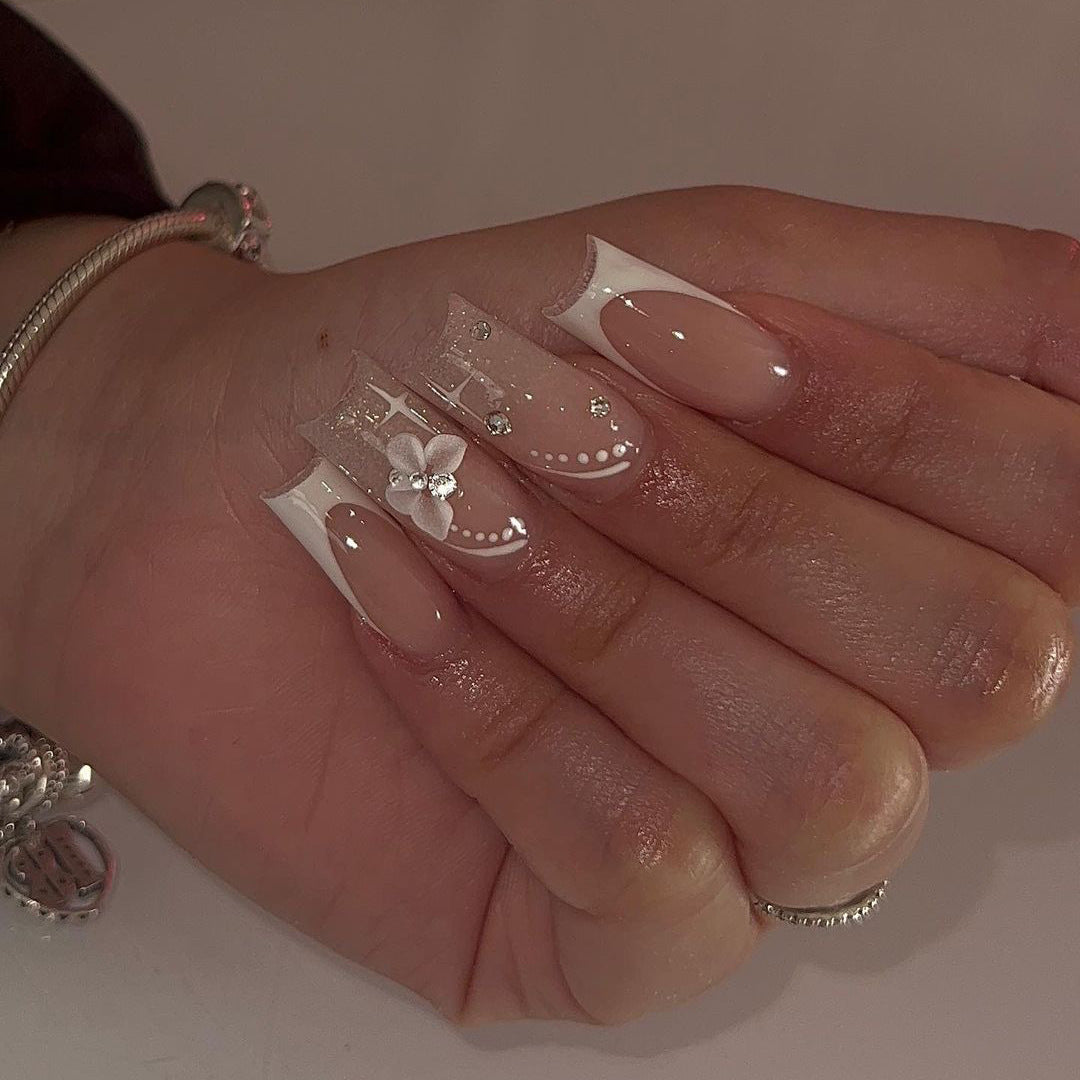 Elegante Kunstnägel mit floralen Designs und Glitzerakzenten Karnz