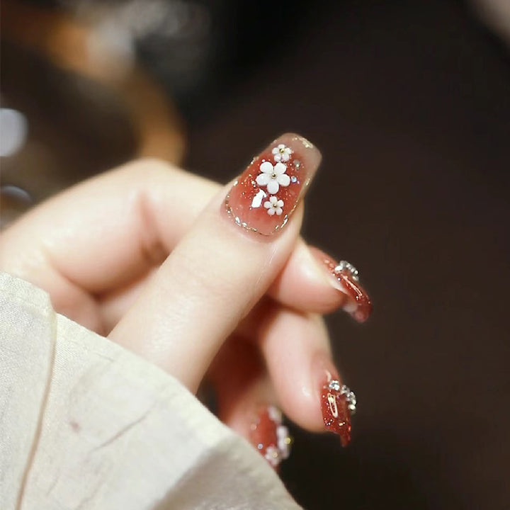 Künstlerische Press-On Nagelkunst mit floralen und Glitzerakzenten Karnz