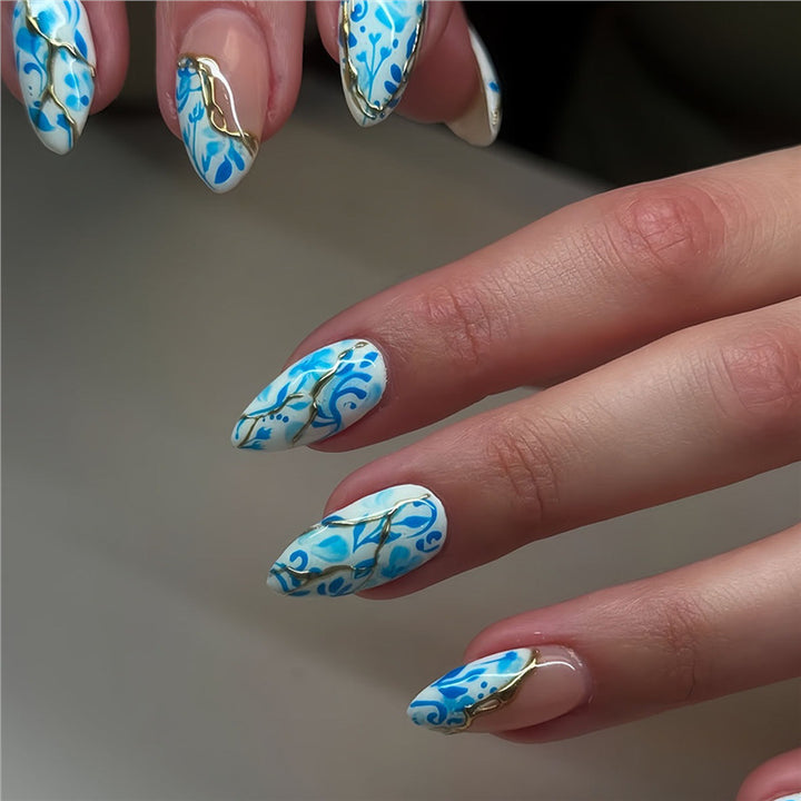 Künstlerisches florales Press-On-Nageldesign mit goldenen Akzenten Karnz