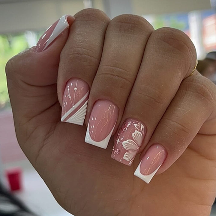 Kunstvolle Nagelkunst mit eleganten französischen Spitzen und floralen Akzenten Karnz
