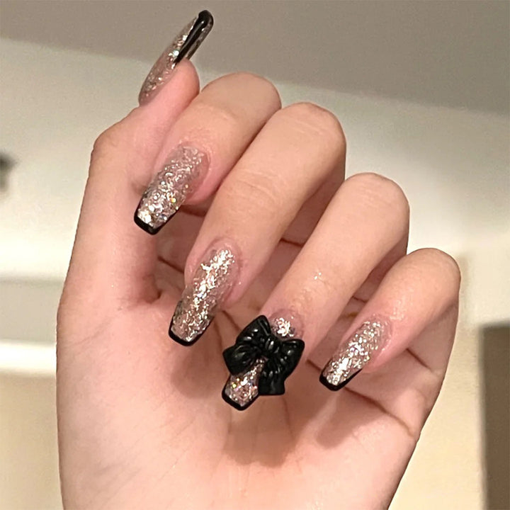 Kunstvolle Nagelverlängerungen mit Glitzer- und Schleifenakzenten Karnz