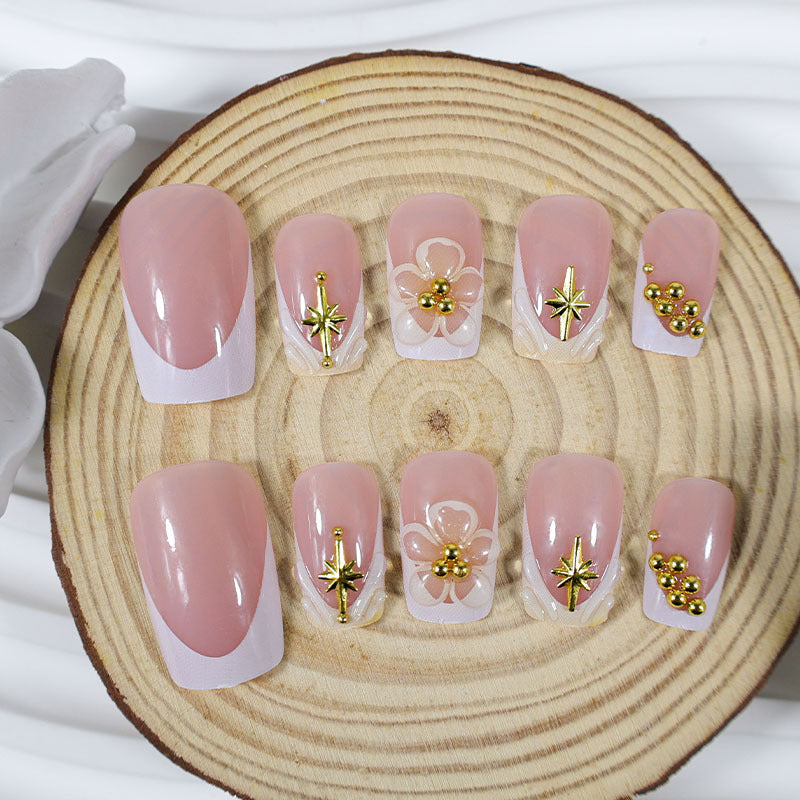 Kunstnagelset mit zarten Blüten- und Goldverzierungen Karnz