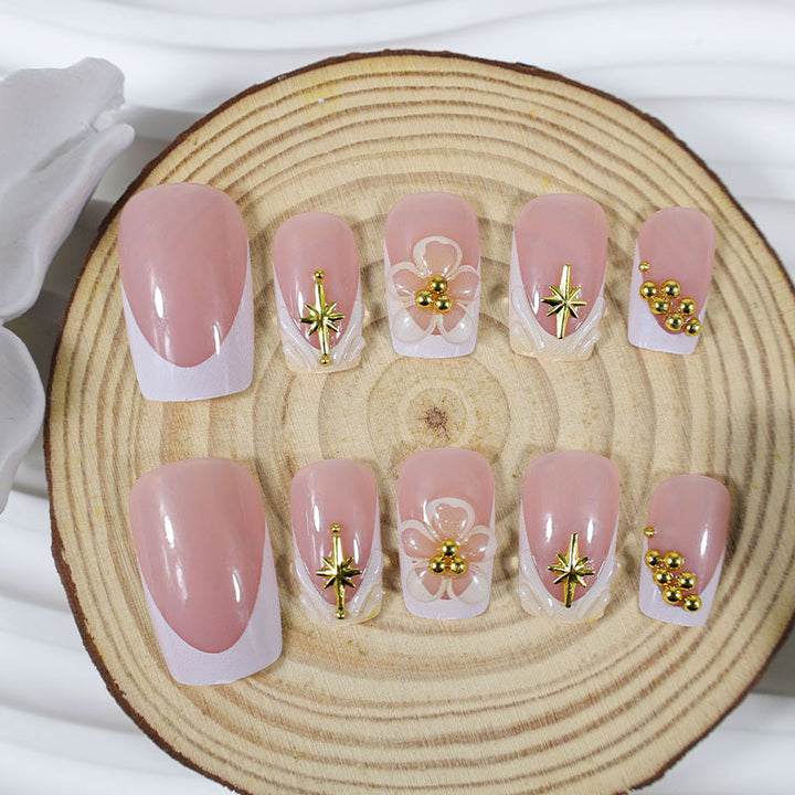 Kunstnagelset mit zarten Blüten- und Goldverzierungen Karnz