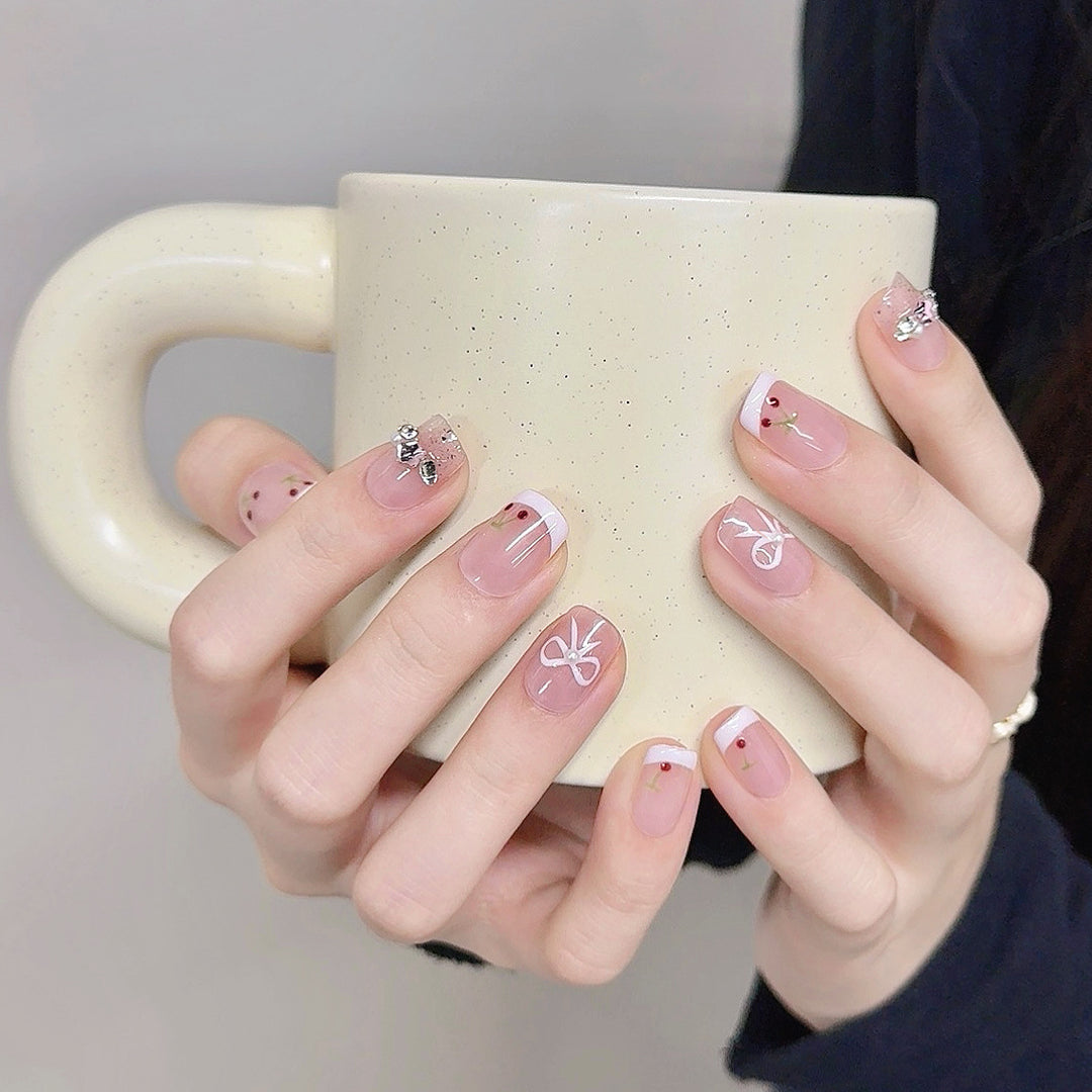 Dekorative Press-On-Nagelkunst mit floralen und Schleifenakzenten