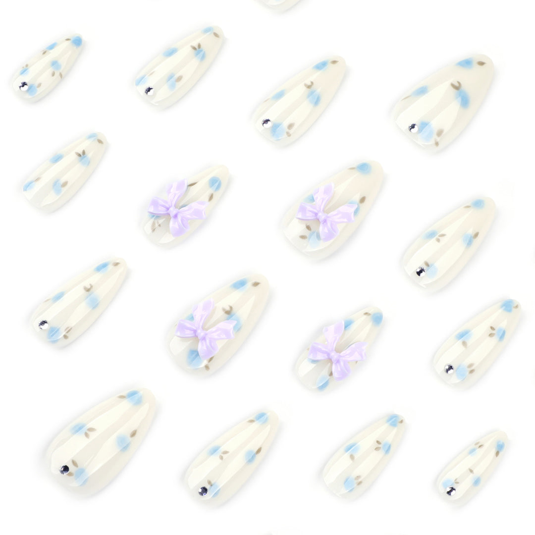Kunstvolle Stiletto-Nägel mit zarten Blütenmotiven und Glitzerakzenten Karnz