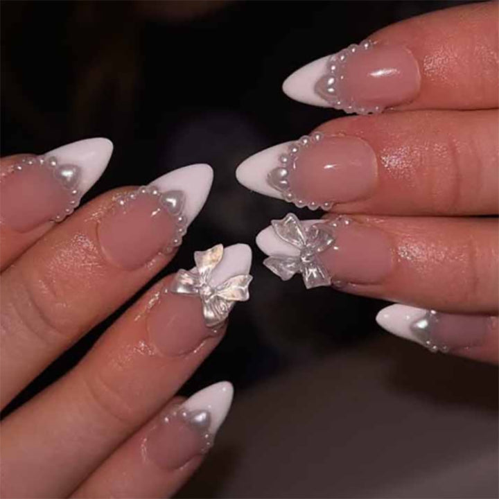 Kunstvolle Nagelverlängerungen mit Perlen- und Schleifenmotiven Karnz