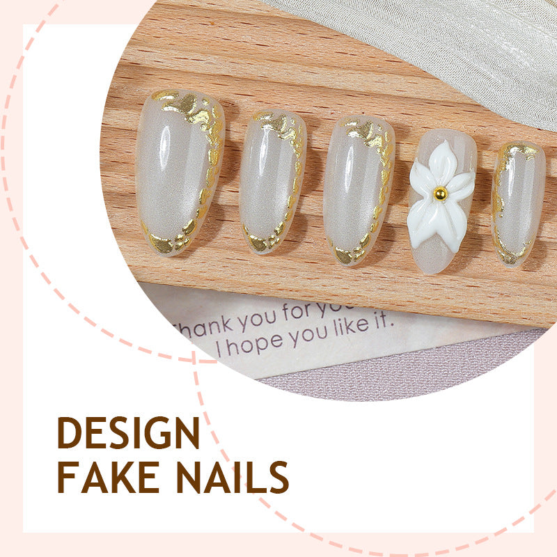 Kunstnagelset mit eleganten Goldverzierungen und floralem Akzent Karnz