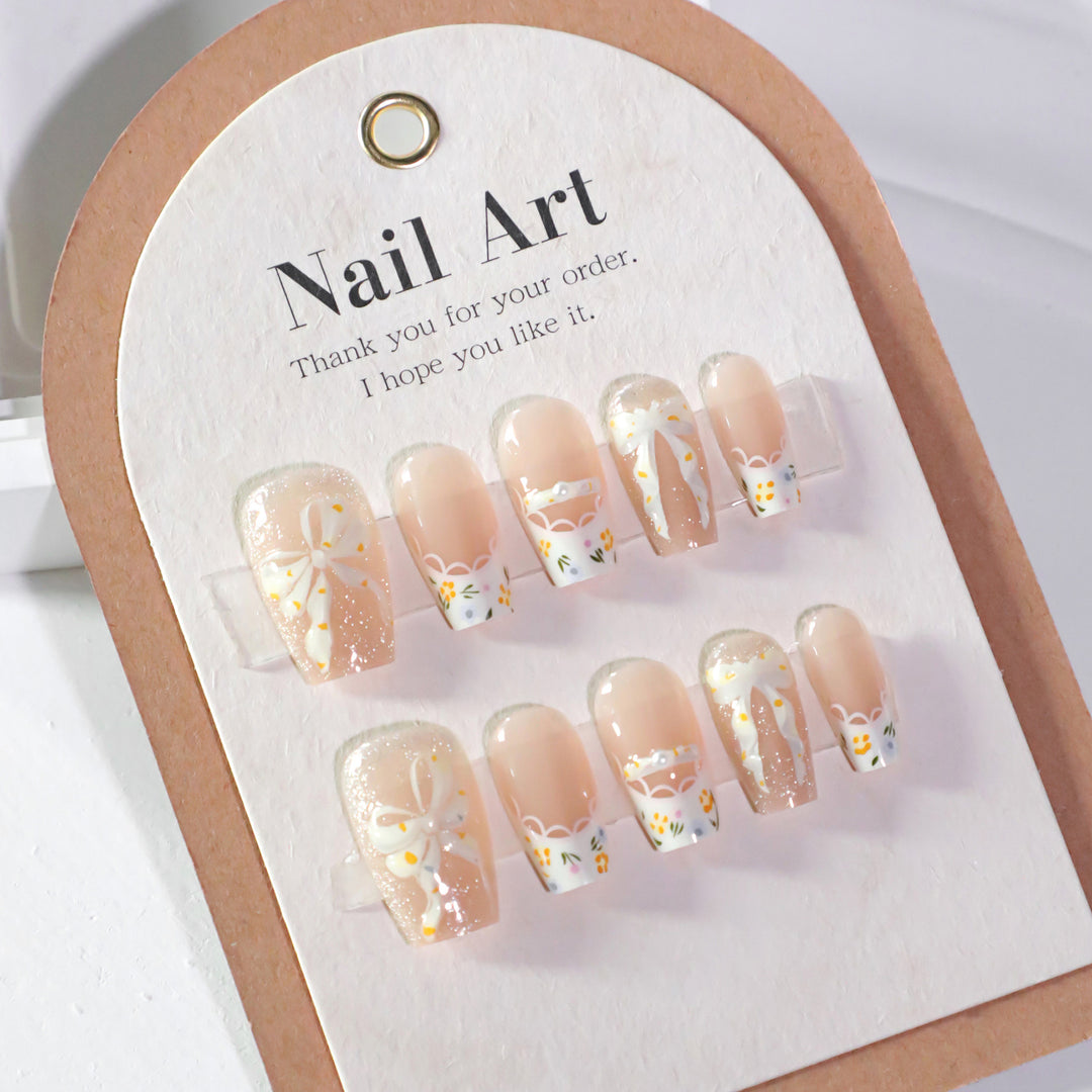 Kunstvolle Nagelverlängerungen mit floralem Design und Schleifenakzenten Karnz