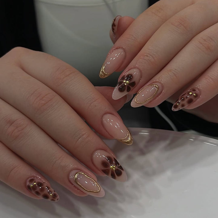 Elegante Kunstnägel mit floralem Akzent und goldenen Details Karnz