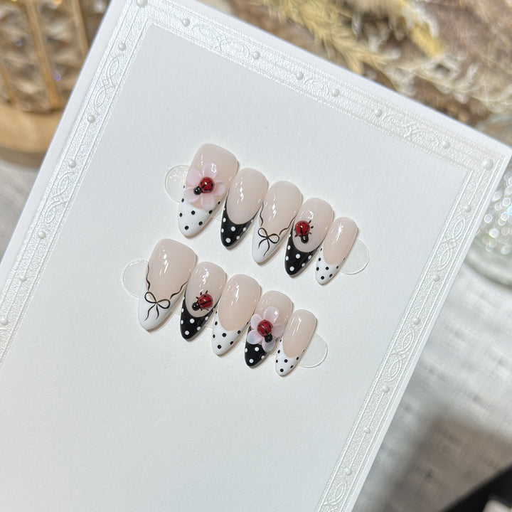Künstlerisches Stiletto Press-On Nail Set mit floralen und Insektenmustern Karnz