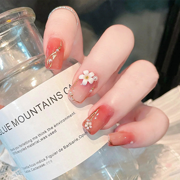 Kunstnagelset mit eleganten Blumendekoren und glamourösen Perlenakzenten Karnz