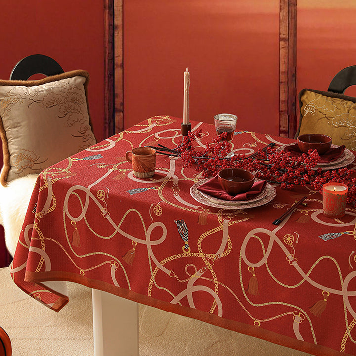 Rechteckige Tischdecke aus pflegeleichtem Polyester‑Mischgewebe mit dekorativem Quasten‑ und Bandmotiv und kontrastierter Saum