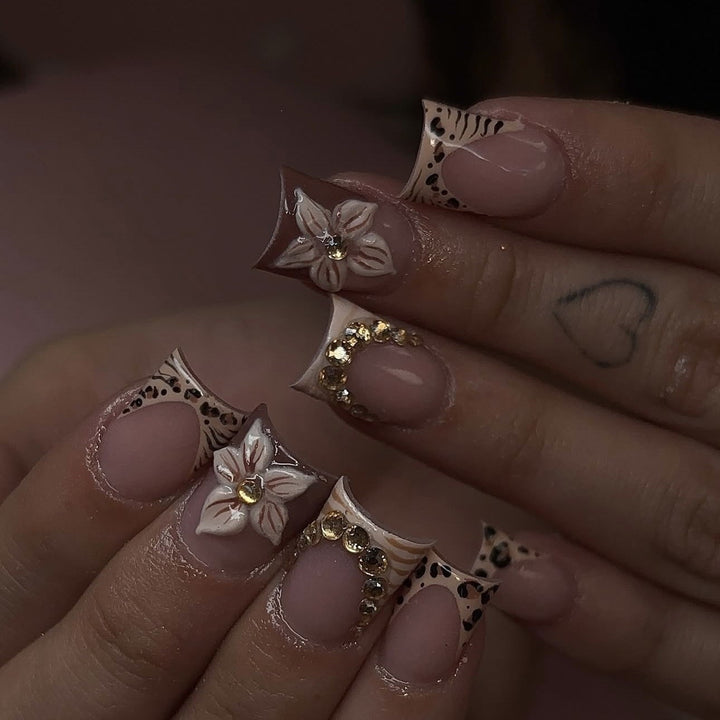Kunstnagelset mit floralen Verzierungen und eleganten Glitzerdetails Karnz