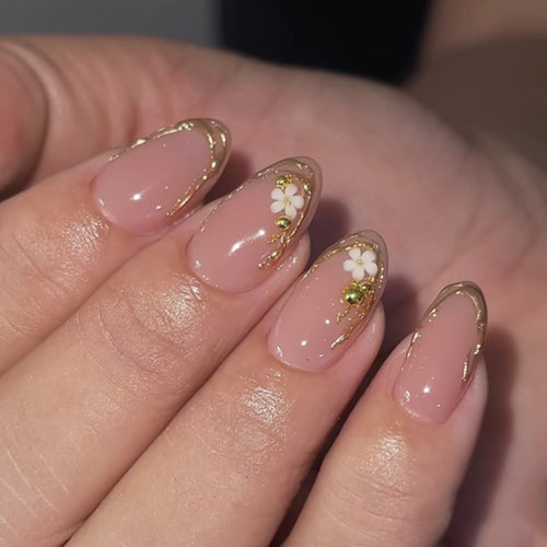 Kunstvolle Nagelgestaltung mit goldenen Akzenten und floralen Details Karnz