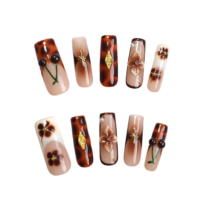 Elegantes Nagelkunstset mit floralen und goldenen Akzenten Karnz