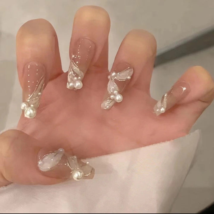 Kunstvolle Nagelkunst mit Schmetterlings- und Perlendetails Karnz