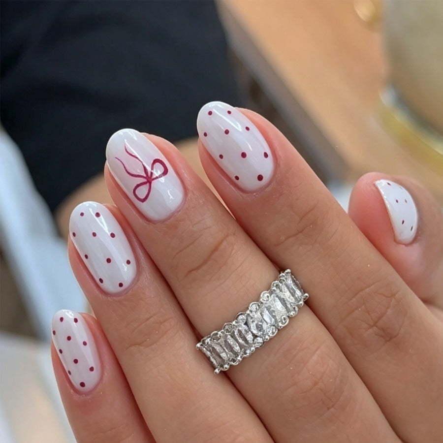 Kunstnagelset mit zarten Punkten und Schleifenmuster Karnz