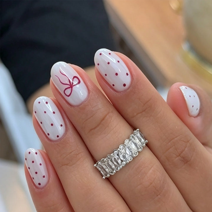 Kunstnagelset mit zarten Punkten und Schleifenmuster Karnz