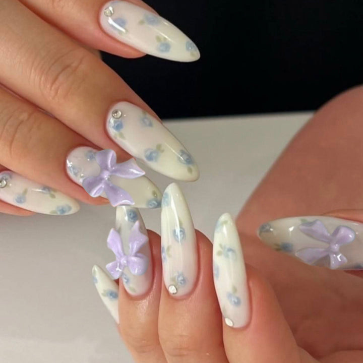 Kunstvolle Stiletto-Nägel mit zarten Blütenmotiven und Glitzerakzenten Karnz