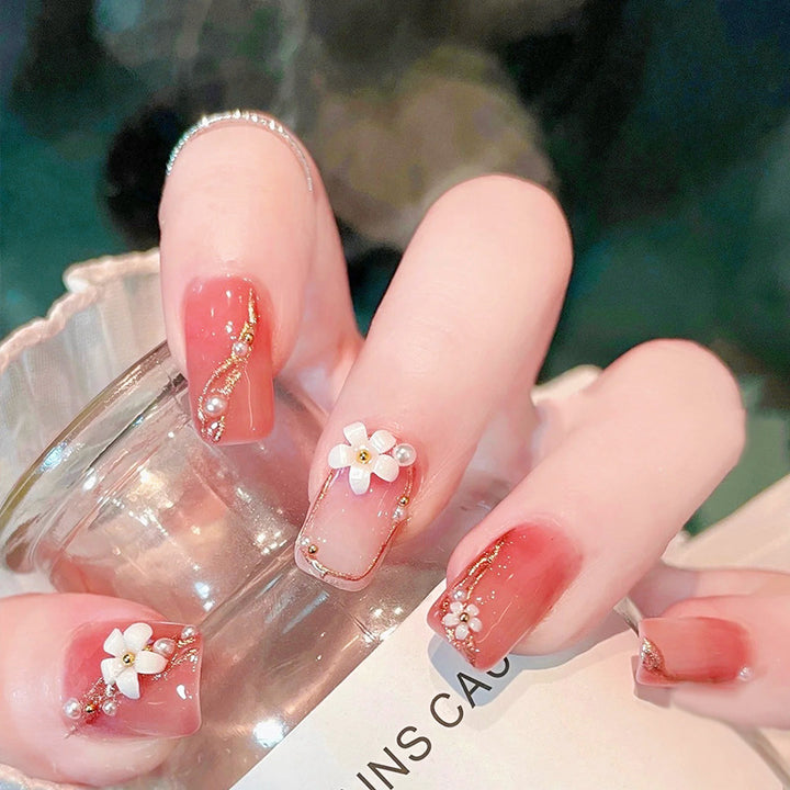 Kunstnagelset mit eleganten Blumendekoren und glamourösen Perlenakzenten Karnz