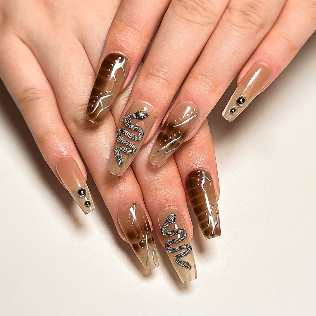 Kunstvolle Fingernägel mit Schlangen- und Glitzerakzenten Karnz