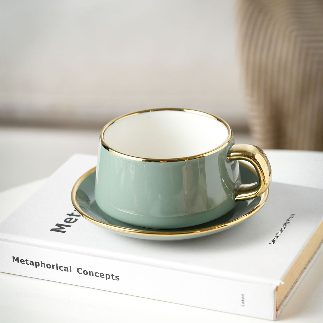 Elegante Porzellan-Tasse mit Untertasse und skulpturellem Goldhenkel