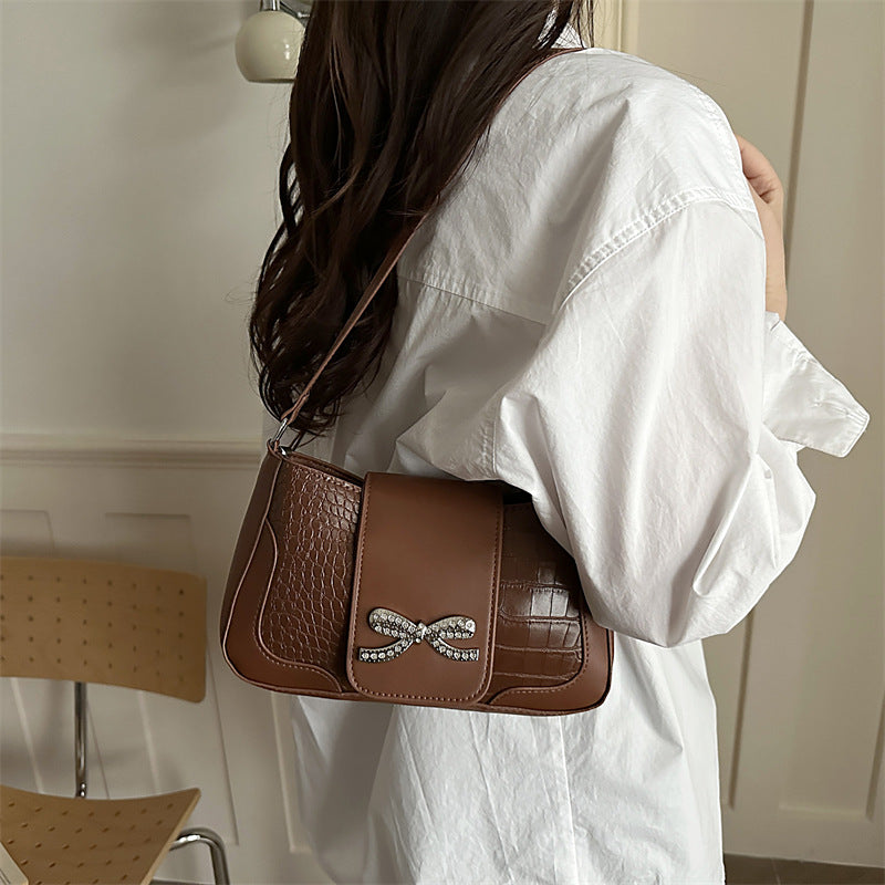 Elegante Handtasche mit Krokodilmuster und Schleifendetail