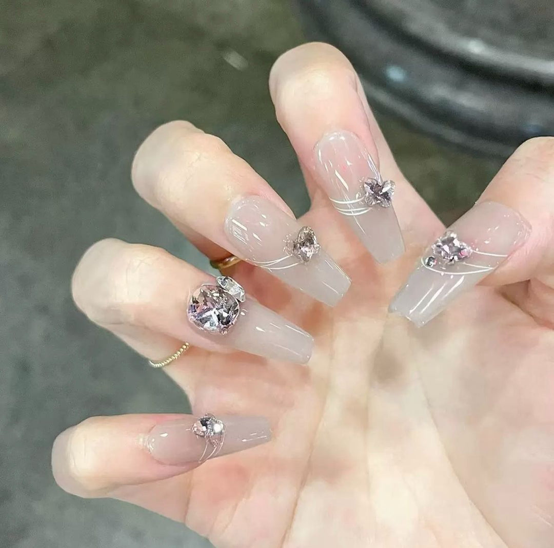 Kunstvolle Nagelkunst mit Schmetterlings- und Perlendetails Karnz