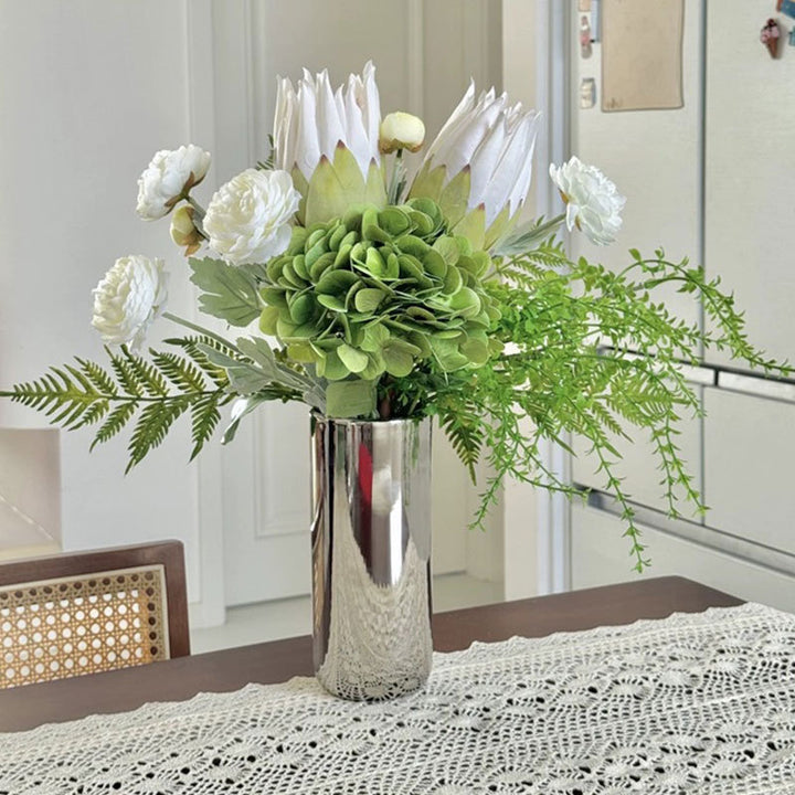 Spiegelnde hohe zylindrische dekorative Metallvase mit künstlicher Hortensie und Protea Arrangement
