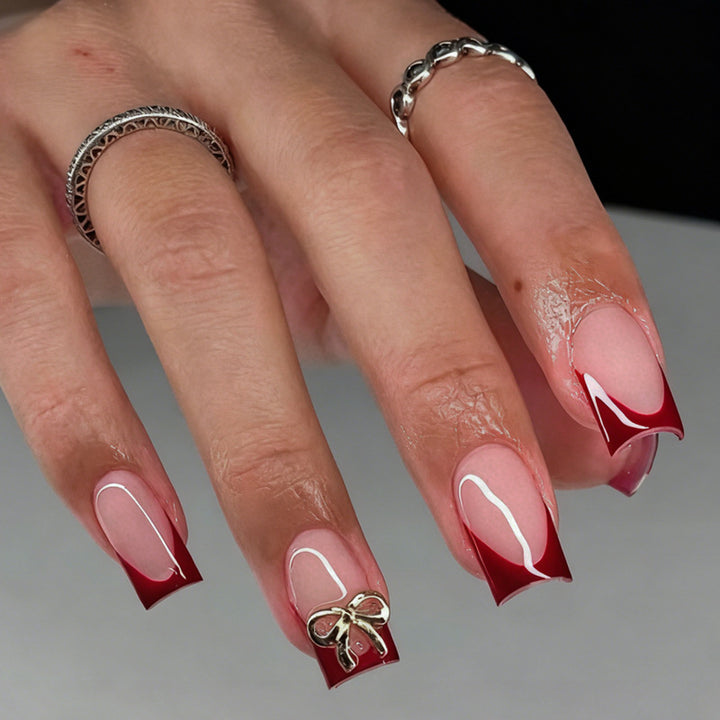 Kunstnagelset mit eleganten roten Spitzen und raffinierten Schleifenverzierungen Karnz