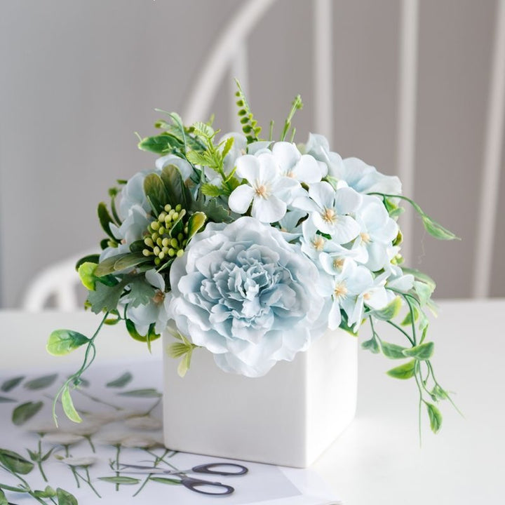 Lebensechte Blumenarrangement in dekorativem quadratischen Pflanzgefäß