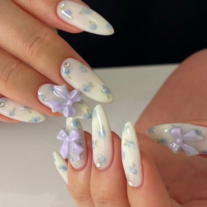 Kunstvolle Stiletto-Nägel mit zarten Blütenmotiven und Glitzerakzenten Karnz