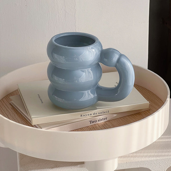 Skulpturaler Keramikbecher mit irisierender Glasur und gewölbtem Ringhenkel